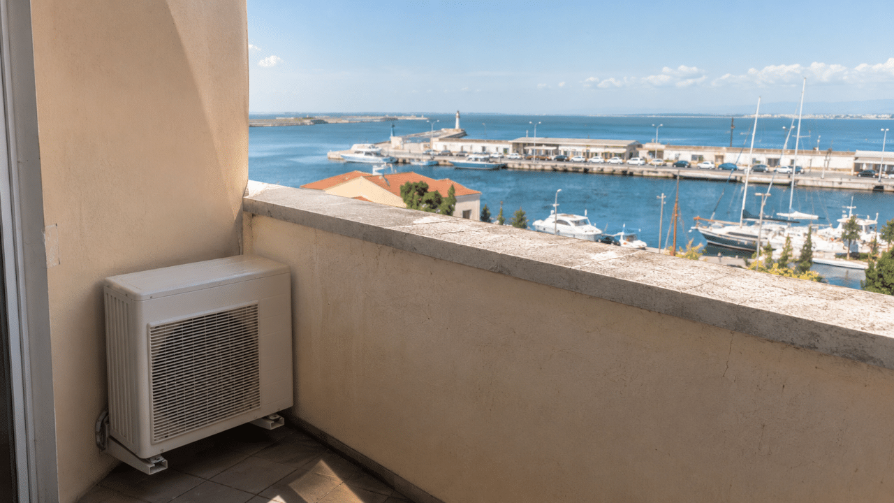 Unité extérieure de climatisation sur un balcon d'appartement à Sète, avec vue sur le port et la mer
